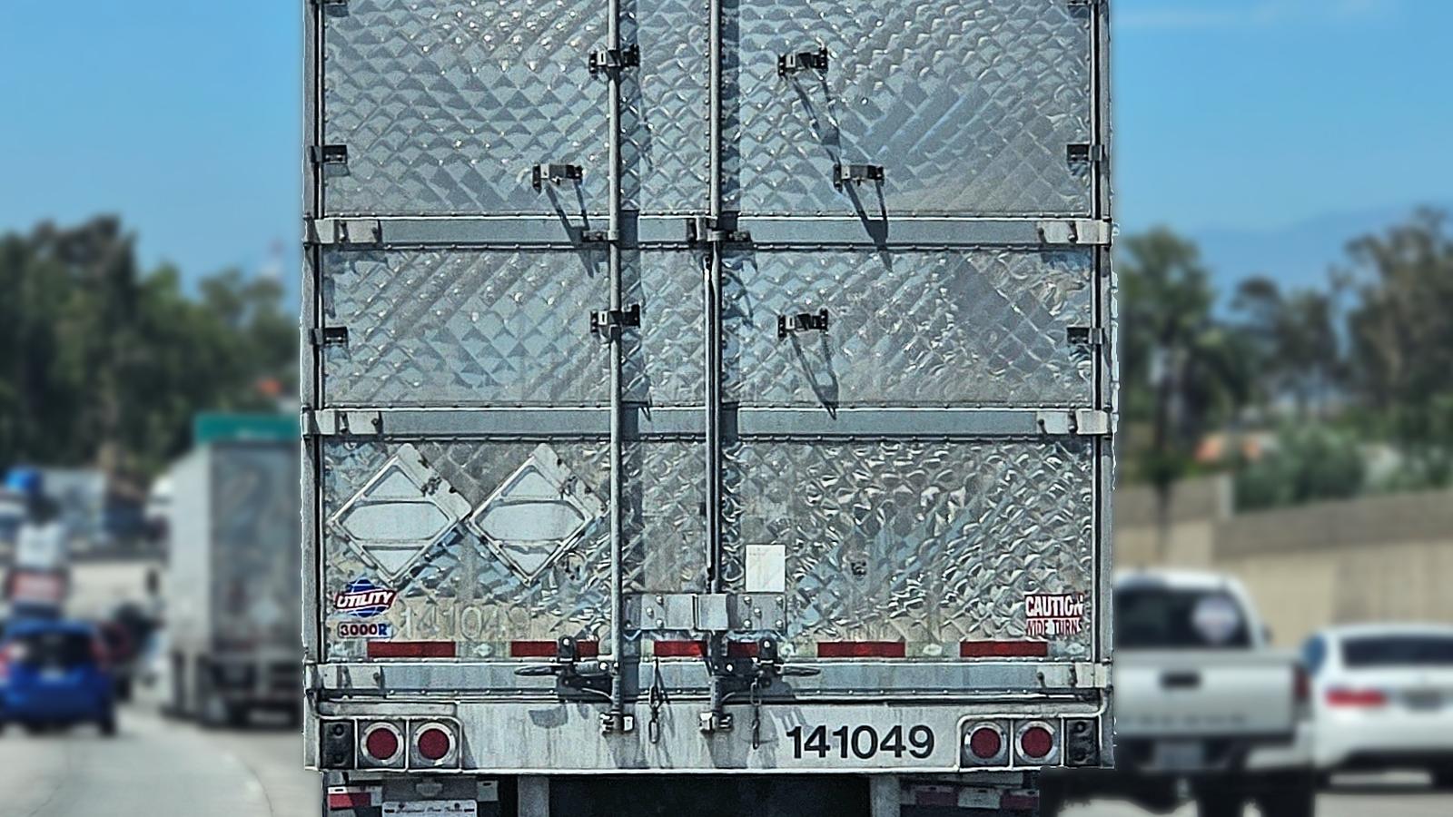 Rear doors of an insulated van semi-trailer on a highway.