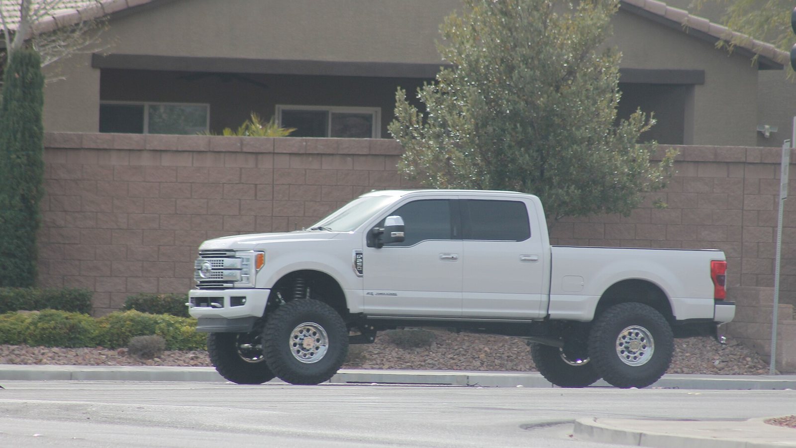 A white Ford F-250 pickup with a raised suspension and oversized tires stopped at an intersection in Las Vegas.