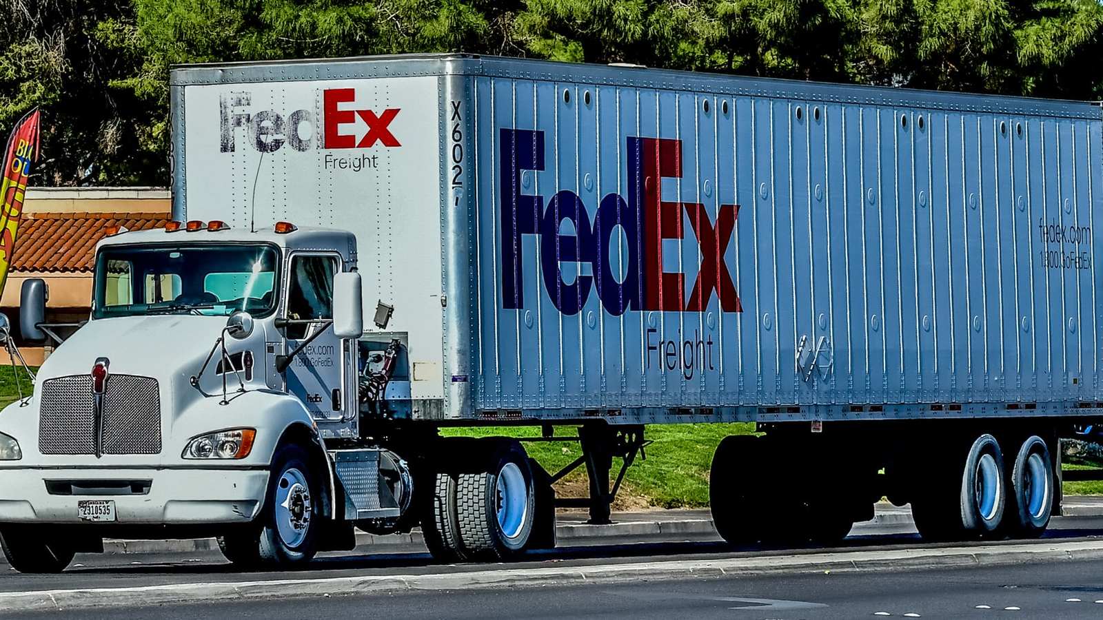 A FedEx Freight tractor pulling a trailer on a road.
